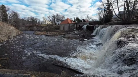 Waterfall flowing beside a historic mill on a river, static shot Stock Footage 337555426