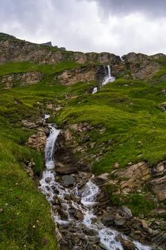 Waterfall flowing down mountain slopes along famous Grossglockner Hochalpenst Stock Photos