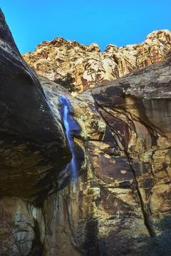 Waterfall Flowing Down Red Rock Canyon Wall Under Bright Blue Winter Sky Stock Photos