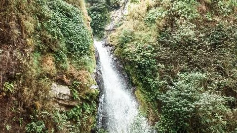 A waterfall is flowing down a rocky cliff 스톡 사진