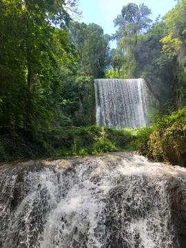 A waterfall is flowing down a rocky hillside Stock Photos