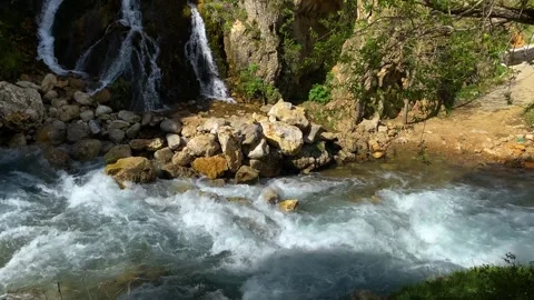 Waterfall flowing next to rocks in the forest Stock Footage 273320832