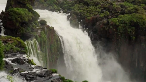 Waterfall flowing over green mossy boulders surrounded by tropical plants in Stock-Footage 345027352