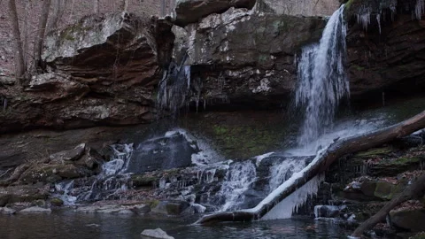 Waterfall flowing over ice covered rocks in a forest Video stock 298133158