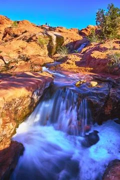 Waterfall Flowing Over Red Rocks and Visitors at Gunlock State Park Utah Stock Photos