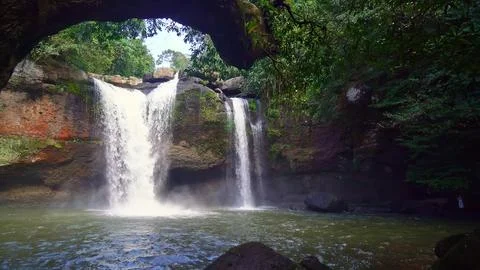 Waterfall flowing over rocks in a lush green forest Stock Photos