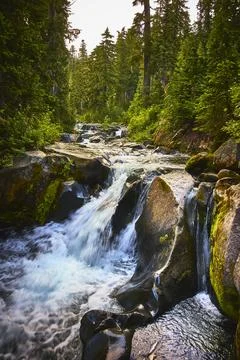Waterfall Flowing Over Rocky Stream in Lush Forest Landscape Stock Photos