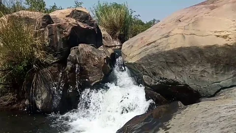 A waterfall Flowing, passing down between two large rocks in the daylight. Stock Footage 95722612