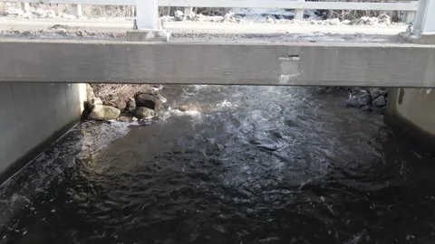 Waterfall flowing into stream beneath bridge in Paradox NY Stock Footage 268444750