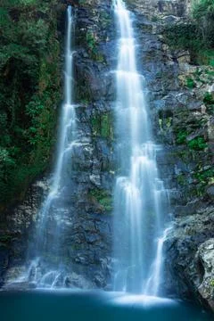 Waterfall flowing streams falling from mountain with calm blurred water surfa Stock-Fotos