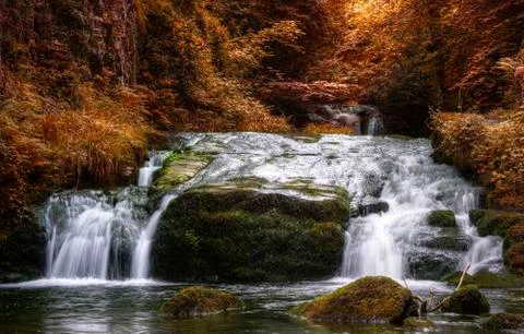 Waterfall flowing through autumn fall forest landscape Stock Photos