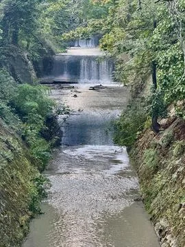 Waterfall Flowing Through a Green Forested Landscape Stock Photos