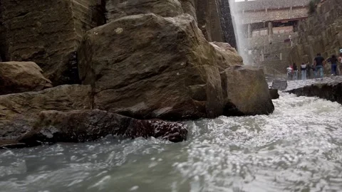 Waterfall Flowing Through Rocky Gorge with Large Boulders and Stone Paths in Vídeos de archivo 345143315