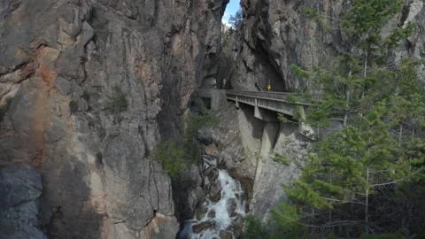 Waterfall Flowing Underneath Road Bridge Through Mountain Valley Stock Footage 232050041