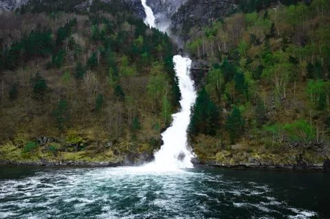 Waterfall flows down among the mountains - Flam in Norway Stock Photos