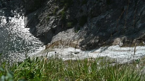 A waterfall flows down behind grass in summer (slow motion) Stock-Footage 219644165