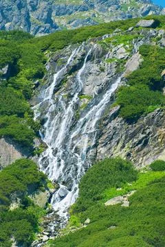 A waterfall flows down a mountain slope. Beautiful summer landscape in the Ta Stock Photos
