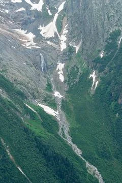 Waterfall flows down rocky mountain in summer Stock Photos