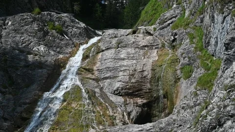 A waterfall flows over rocks in the mountains (slow motion) Video stock 219644887