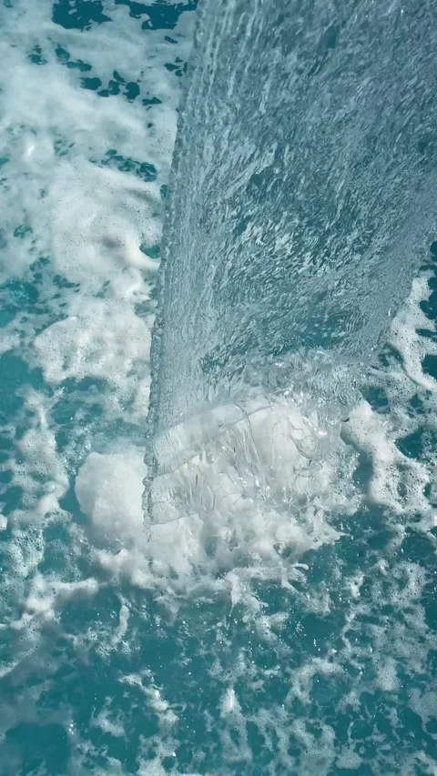 A waterfall flows into a spa pool under the open sky, creating a relaxing and Stock Footage 302470601