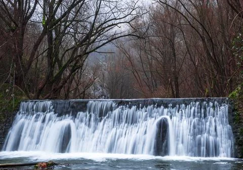 A waterfall that flows surrounded by trees Stock Photos