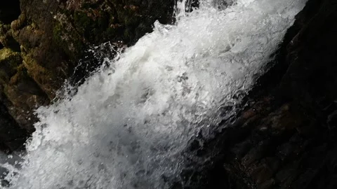 A waterfall flushes between rocks and creates bubbles (slow motion) Video stock 219396472