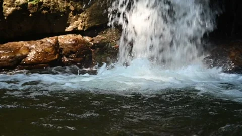 A waterfall flushes into a pool and creates bubbles (slow motion) Video stock 219393201