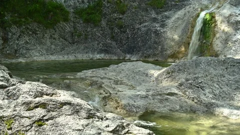 A waterfall is flushing into a natural pool, and the water is flowing further 스톡 동영상 211743722