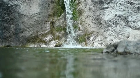Waterfall flushing over rocks into a natural pool with green water (slow motion) Stock Footage 211763309