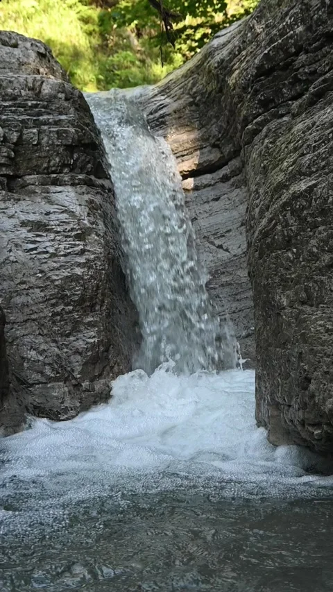 A waterfall flushing into a pond between rocks, slow motion, vertical shot, Wolf 스톡 동영상 288325199