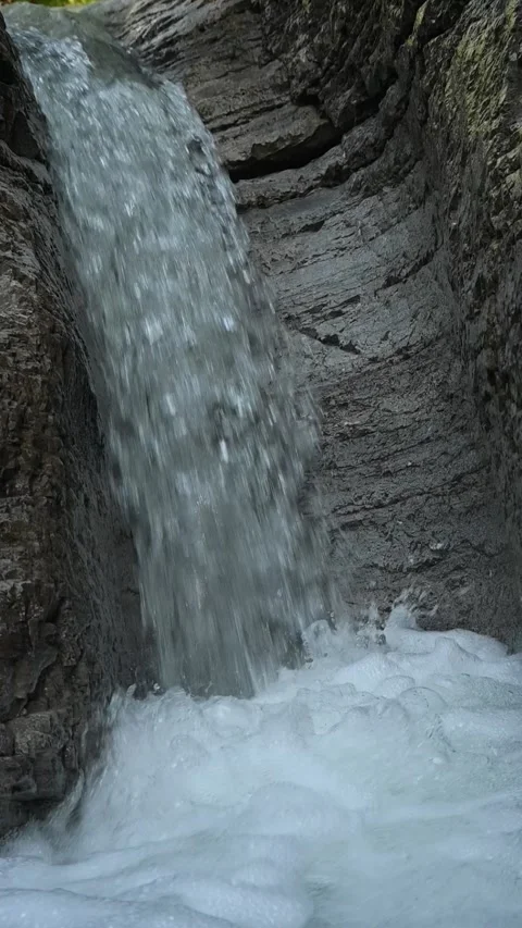 A waterfall flushing into a pond between rocks, slow motion, vertical shot Stock Footage 288325459