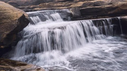 Waterfall with foamy texture surrounded with rocks and mountains 写真素材