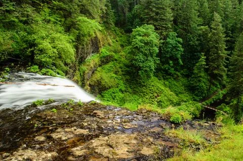 Waterfall in forest with bridge in background Stock Photos