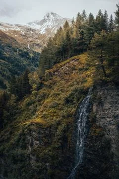 A waterfall in a forest with mountains in the background Stock Photos
