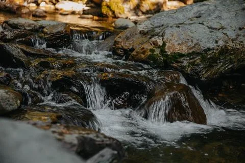 A waterfall is in a forest, surrounded by trees and rocks Stock Photos