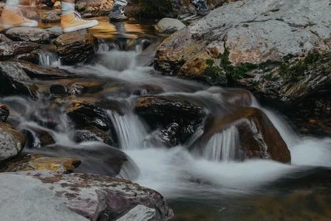 A waterfall is in a forest, surrounded by trees and rocks Stock Photos