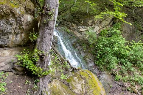 A waterfall, a fragment of a mountain river in the embrace of a stone canyon Stock Photos