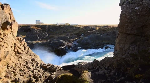 Waterfall with heavy flow and spray, with houses in background 库存影片 68540393