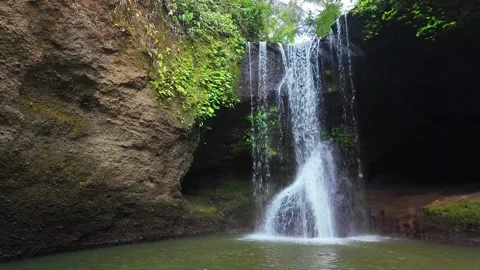 Waterfall hidden deep within Bali jungle, surrounded by vibrant foliage and.. Stock Footage 331047776
