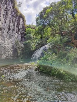 Waterfall in the middle of the forest in front of the wall Stock Photos