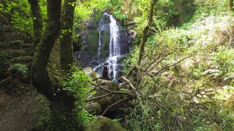 Waterfall in the middle of the forest or woods and girl relaxing in nature Vidéo 285767332