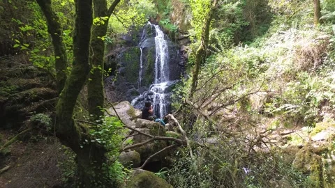 Waterfall in the middle of the forest or woods and girl relaxing in nature Vidéo 285767855