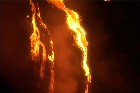 A waterfall of molten lava  trickles down a steep slope during a volcanic Stock-Footage 24948936