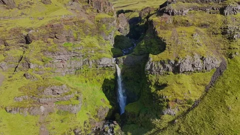 Waterfall in a Mossy Icelandic Gorge as Camera Pulls Back Stock Footage 342267179