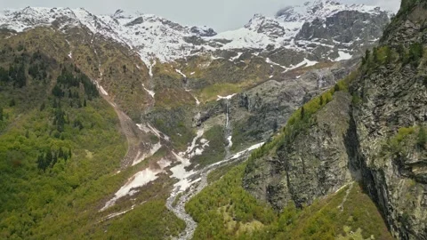 Waterfall in mountains from glacier, mountains covered snow, aerial view Stock Footage 277006165