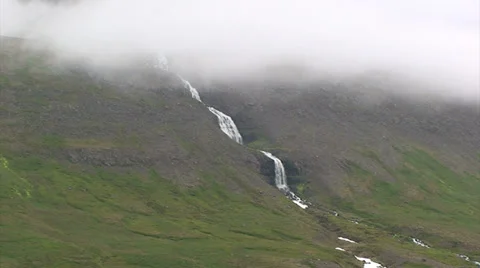Waterfall with multiple sections flows down from the low clouds Stock Footage 37271806