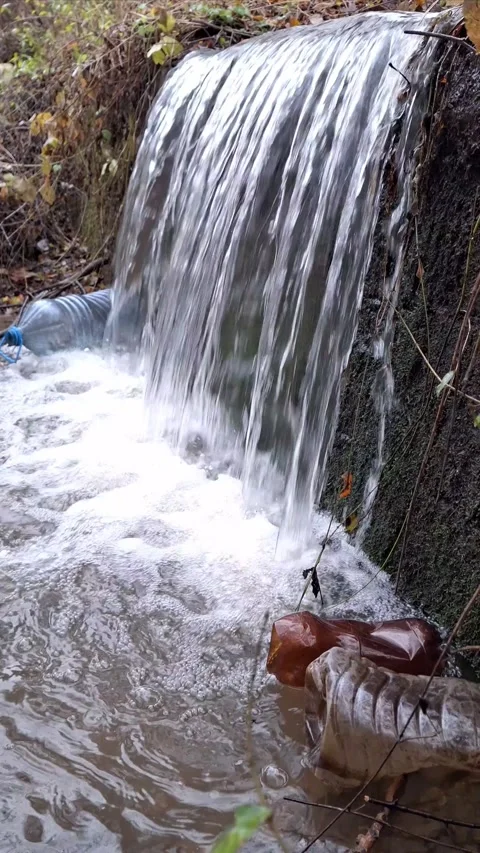 A waterfall in a natural setting polluted with plastic bottles Stock Footage 294320560