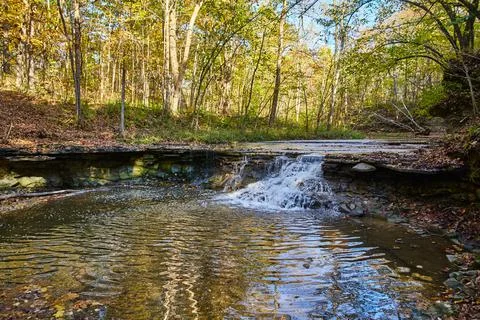 Waterfall over slates of rocks in fall forest Foto stock