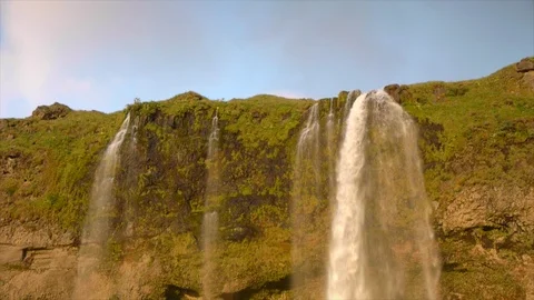Waterfall plunging over side of Iceland cliff face, bathed in warm golden glow. Stock Footage 86755091