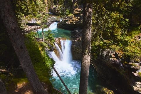 Waterfall Plunging Into Turquoise Pool Surrounded by Lush Forest and Rocky Foto stock